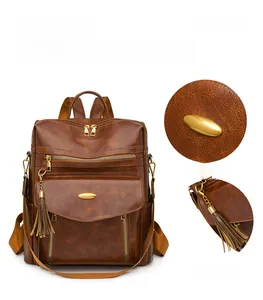 Detail view of vintage brown PU leather backpack with tassel charms and gold hardware