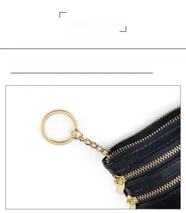 Detail view of black litchi pattern leather coin purse with triple golden zippers and key ring