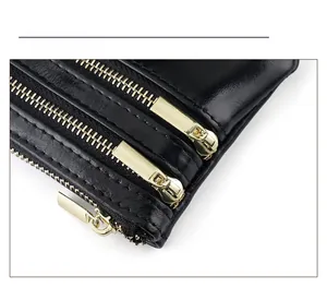 Detail shot of three smooth gold zippers on black waxed leather wallet pocket