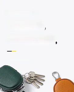 Close-up of litchi grain leather coin pouches in green and orange with metal zippers