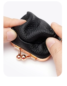 Gros plan d'un porte-monnaie en cuir noir grainé montrant la souplesse et le fermoir or rose