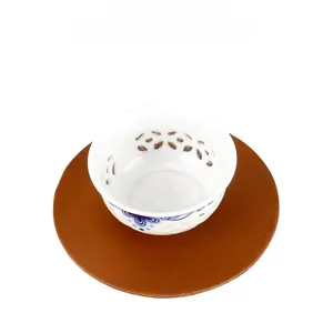 Top-down view of a dark brown crazy horse leather heat-resistant coaster with a tea cup
