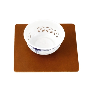 Close-up of a blue and white porcelain tea cup with a brown crazy horse leather coaster