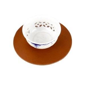 Blue and white ceramic teacup with hollow pattern on a crazy horse leather coaster