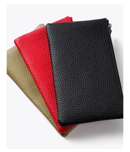 Detailed view of three pebbled leather clutches in black, red, and sage green with zippers
