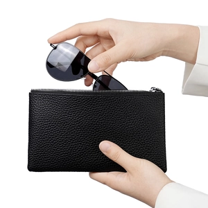 Minimalist black leather clutch pouch with zipper showing capacity for sunglasses