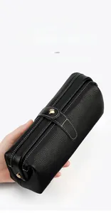 Macro view of black pebbled leather cosmetic bag with white contrast stitching and gold clasp