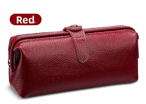 Detail of red lychee grain leather makeup bag with white stitching and gold metal clasp