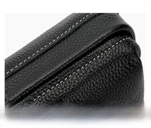 Close-up of black leather makeup bag showing detailed white stitching and pebbled texture