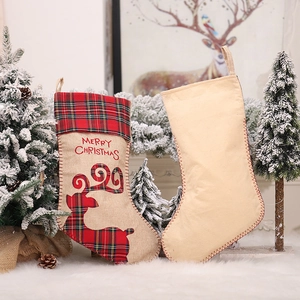 Set mit zwei rustikalen Weihnachtssocken mit Rentierstickerei und Karo-Besatz auf Teppich