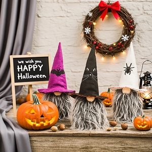 Three Halloween faceless gnomes with pointed hats on a wooden table with pumpkins