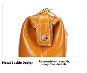 Dettaglio del bottone in metallo argentato e cuciture a contrasto su borsa in pelle cerata