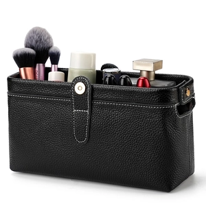 Black leather toiletry bag with white stitching and gold snap closure for cosmetics