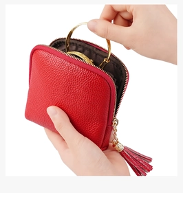 Close-up of red pebbled leather jewelry pouch with gold ring handle and tassel detail