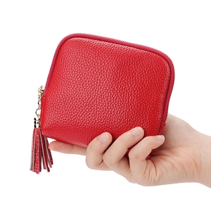 Red lychee grain leather jewelry pouch with gold zipper and tassel held in hand