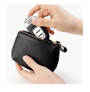 Detail der schwarzen Kieselleder-Münztasche mit goldenem Reißverschluss und Autoschlüsseln