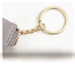 Details von echtem grauem Leder mit goldener Reißverschluss-Kette und Schlüsselring