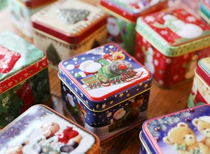 Close-up of square Christmas tin boxes with embossed Santa and snowman holiday patterns