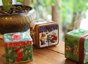 Detail of Christmas tin gift boxes with festive bear and tree patterns on wooden table