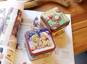 Detailed view of Christmas square tin boxes featuring embossed cartoon teddy bear designs