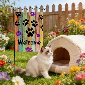 Garden welcome flag with pet paw prints and cat bed in a sunny outdoor floral yard