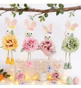 Close-up of four Easter bunny ornaments with fabric flowers hanging on a rustic branch