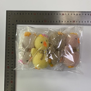 Detailed view of four colorful plush chicks with flower bows and size measurement ruler