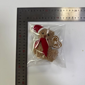 Vista dettagliata dell'orsetto di peluche natalizio marrone con cappello rosso di 10 cm
