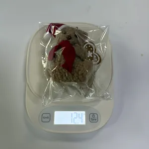 Misurazione del peso di un orsetto di peluche marrone da 12,4g con cappello di Natale