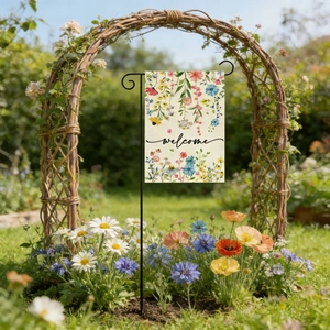 Garden welcome flag with colorful floral patterns and black metal stand in a sunny yard