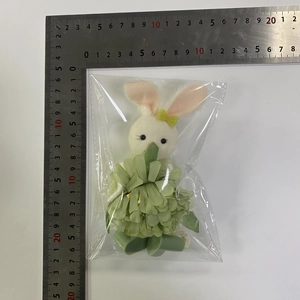 Detail view of Easter bunny plush pendant with green leaf skirt measuring 10cm on ruler