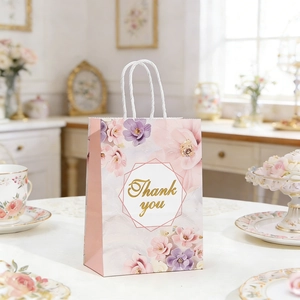 Close-up of pink floral gift bag with gold Thank You script and white rope handles