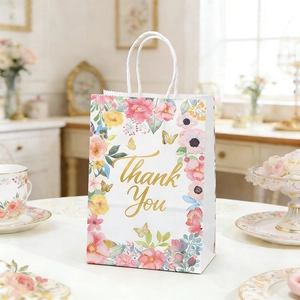 Floral gift bag with 'Thank You' text on a table with tea set and elegant decor