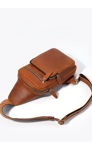Close-up of adjustable strap and metal buckle on brown genuine leather chest bag