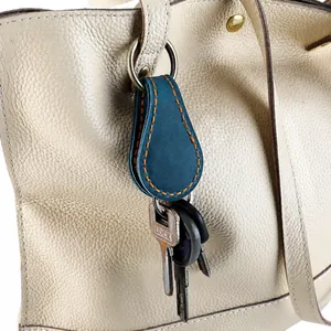 Clip magnétique en cuir bleu paon avec coutures orange sur un sac à main