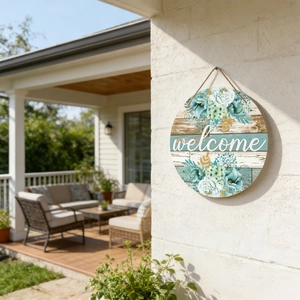 Close-up of a round wooden welcome sign with blue floral motifs on a white wall