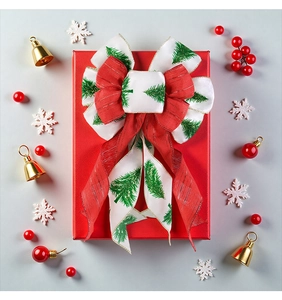 Detail of Christmas bow with tree print and gold edges on a festive red gift box