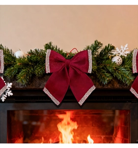 Detail of a deep red velvet Christmas bow with silver glitter edges on green pine branches