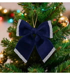 Detail of dark blue velvet Christmas bow with silver glitter edges on a tree branch
