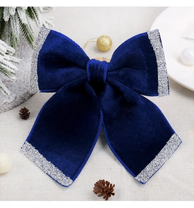 Close-up of royal blue velvet Christmas bow with shimmering silver glitter edges on tree