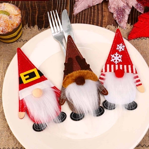 Three festive Christmas gnome felt cutlery holders set on white ceramic dining plates