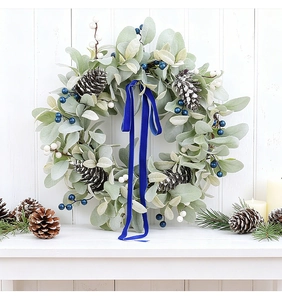 Detail of pine cones, blue berries and velvet ribbon on artificial autumn wreath
