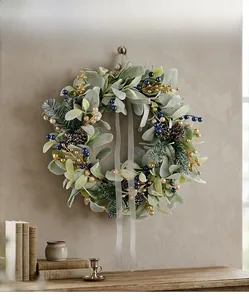 Close-up of winter wreath with artificial leaves, pine cones and berries on a wall