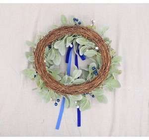 Detailed view of handmade wreath with artificial leaves, pine cones and blue ribbons