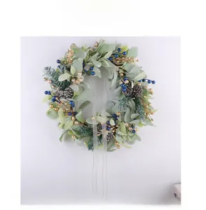 Close-up of Christmas wreath with green leaves, pine cones, and gold blue berries decoration