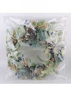 Close-up of artificial Christmas wreath with frosty leaves, berries and pine cones in packaging