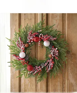 Detail eines Weihnachtskranzes mit roten Beeren, Kiefernnadeln und Zuckerstangen an der Tür