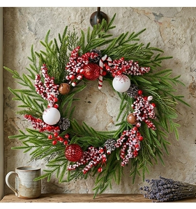 Detailansicht eines Weihnachtskranzes mit roten Beeren, Zapfen und Vintage-Glocken