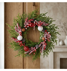 Detailansicht eines Weihnachtskranzes mit Tannennadeln, Beeren und Zuckerstangen an der Holztür