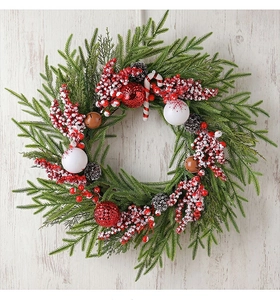 Detail eines Weihnachtskranzes mit Tannenzapfen, Beeren und Zuckerstangen auf Holz